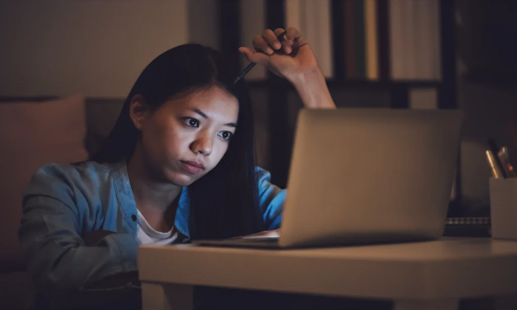 person working on laptop looking overwhelmed and fatigued