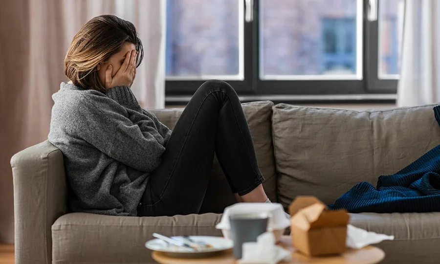 woman sitting on couch feeling emotionally exhausted from burnout and stress
